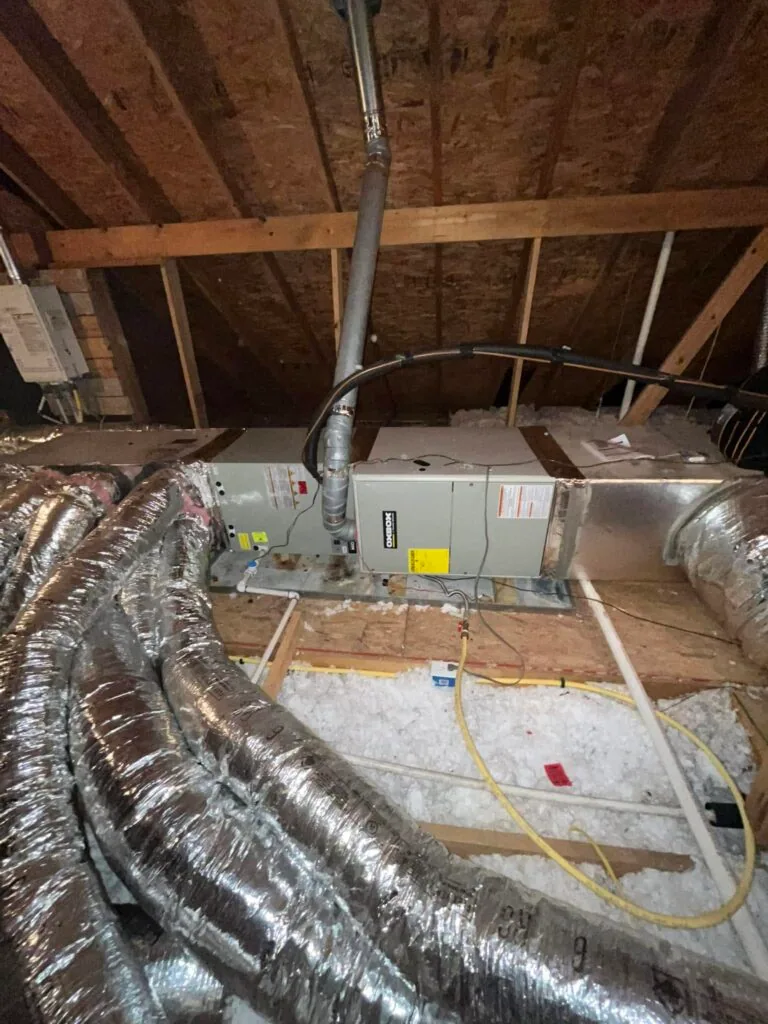 Attic air handler unit with insulated flex ducts, vent pipe, and blown-in insulation between joists
