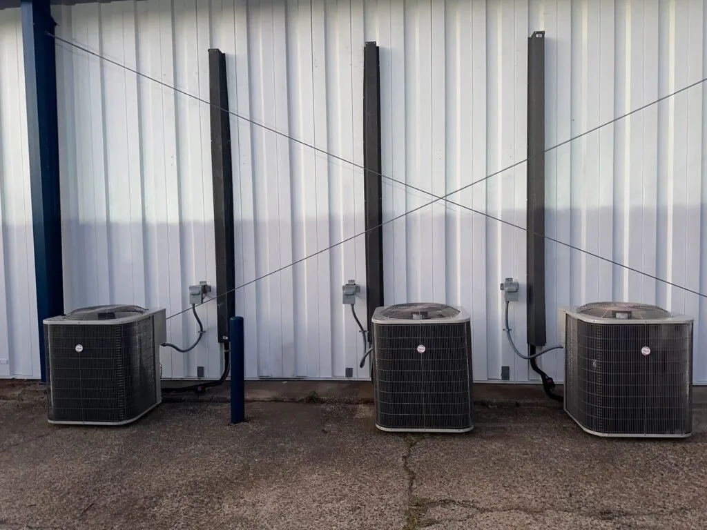Three commercial condenser units mounted against a corrugated metal building wall in West Monroe, LA