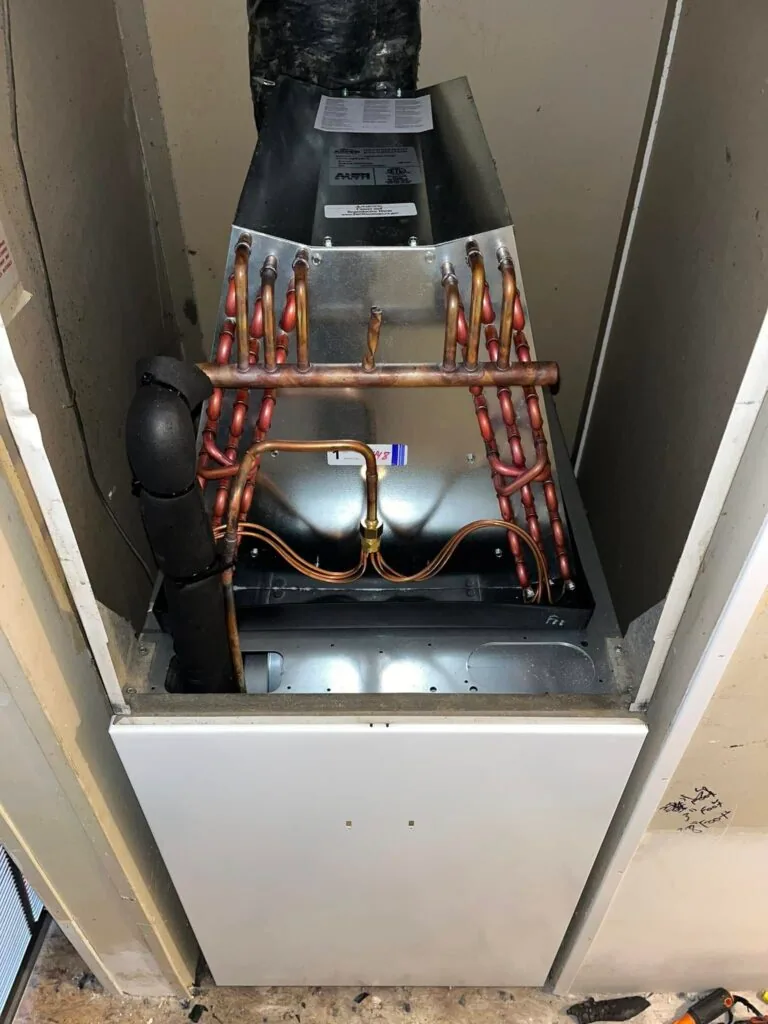 Air handler evaporator coil with exposed copper refrigerant lines in a closet during HVAC installation