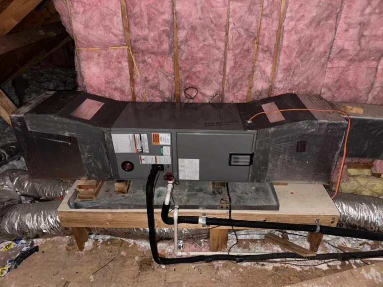 Horizontal HVAC air handler mounted on wood platform in insulated attic with flex duct connections