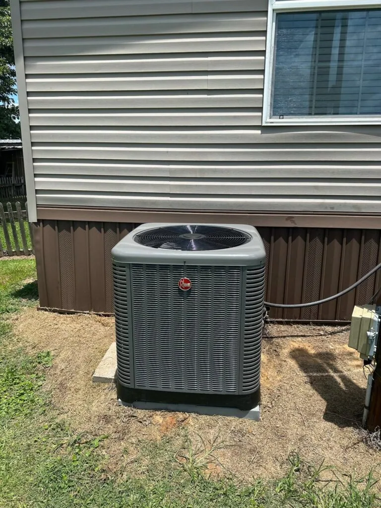 Rheem outdoor condenser unit installed on concrete pad beside vinyl-sided mobile home in West Monroe, LA