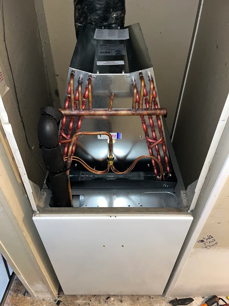 Open air handler closet showing new evaporator coil with copper refrigerant lines during hvac installation